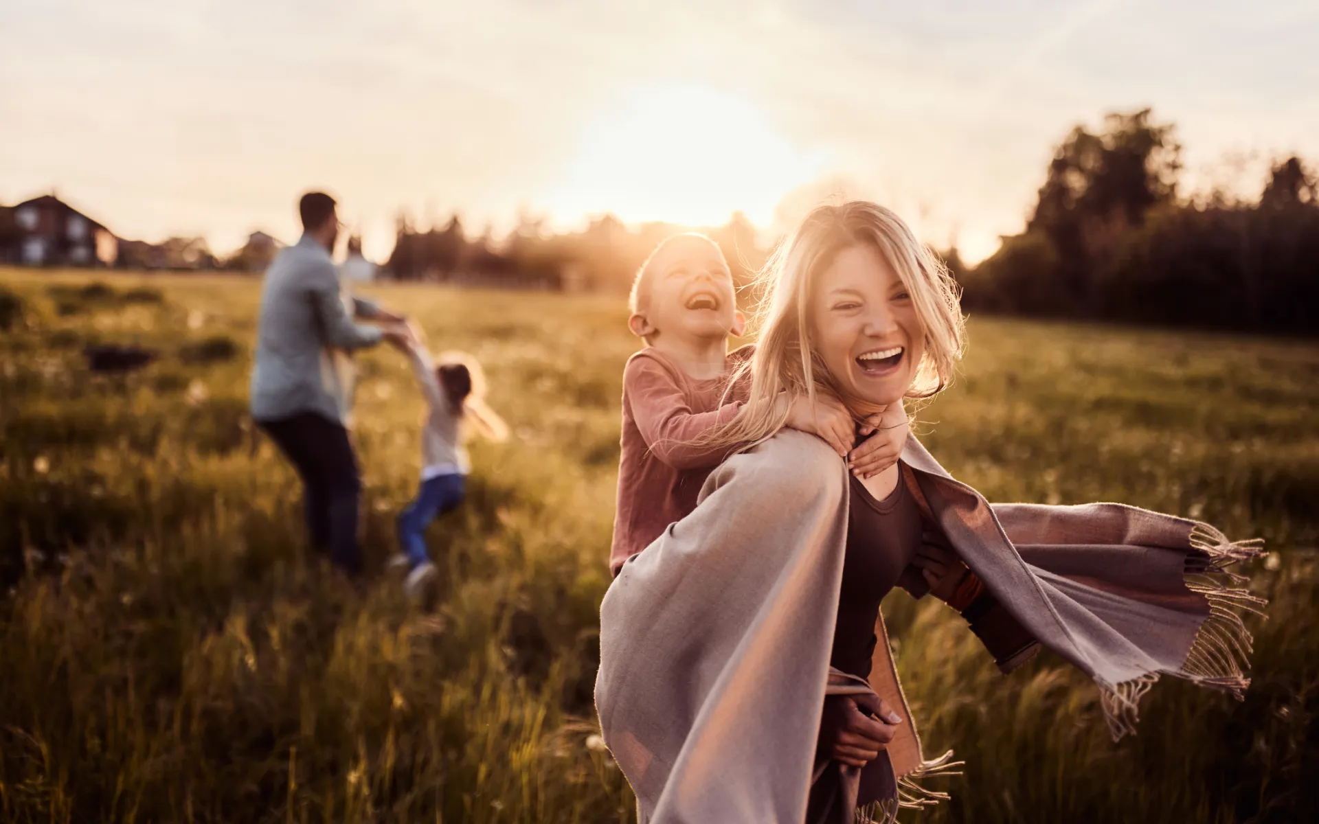 Familj med två barn på en sommaräng i kvällssolen.