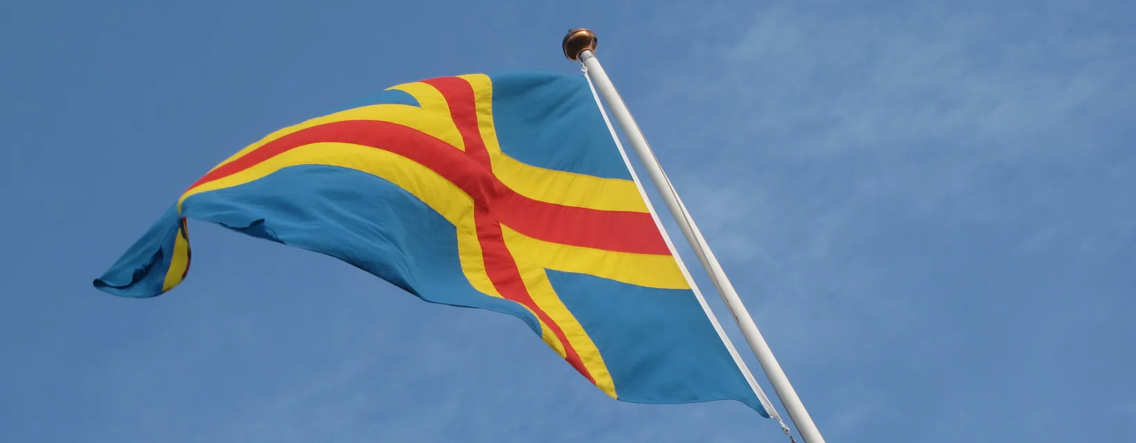 Ålands flagga vajar mot blå himmel.