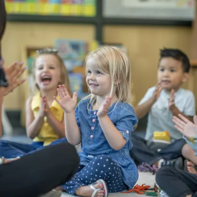 Barn som sitter i ring och skrattar och klappar i händerna på dagis.